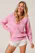 Woman wearing a pink sweater with heart patterns on a plain background