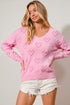 Woman wearing a pink sweater with heart patterns on a plain background