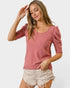 Woman wearing a pink ribbed top and white shorts on a plain background