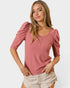 Woman wearing a pink ribbed top with puff sleeves on a white background