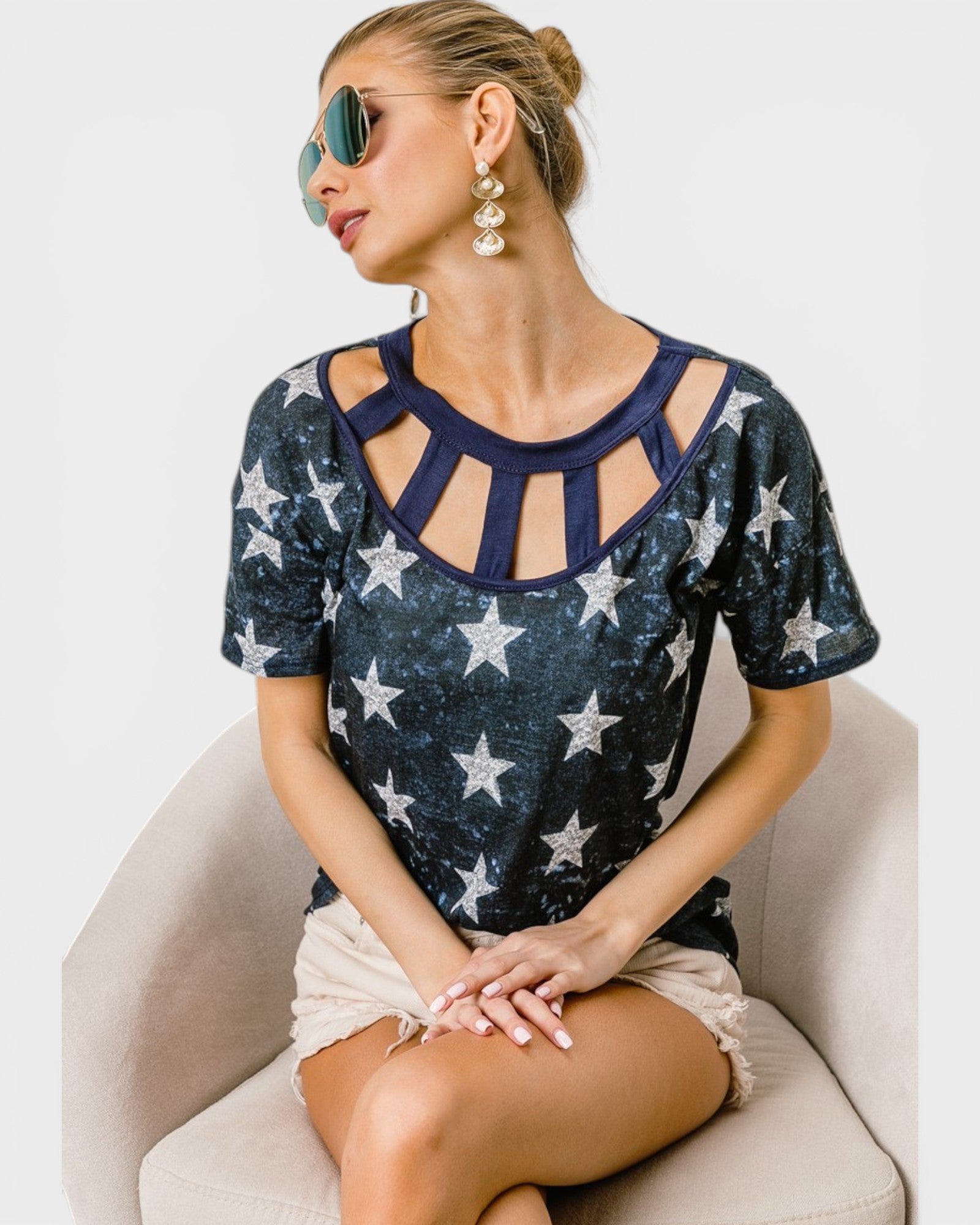Woman wearing a navy blue top with star patterns sitting on a white chair.