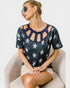 Woman wearing a navy blue top with star patterns sitting on a white chair.