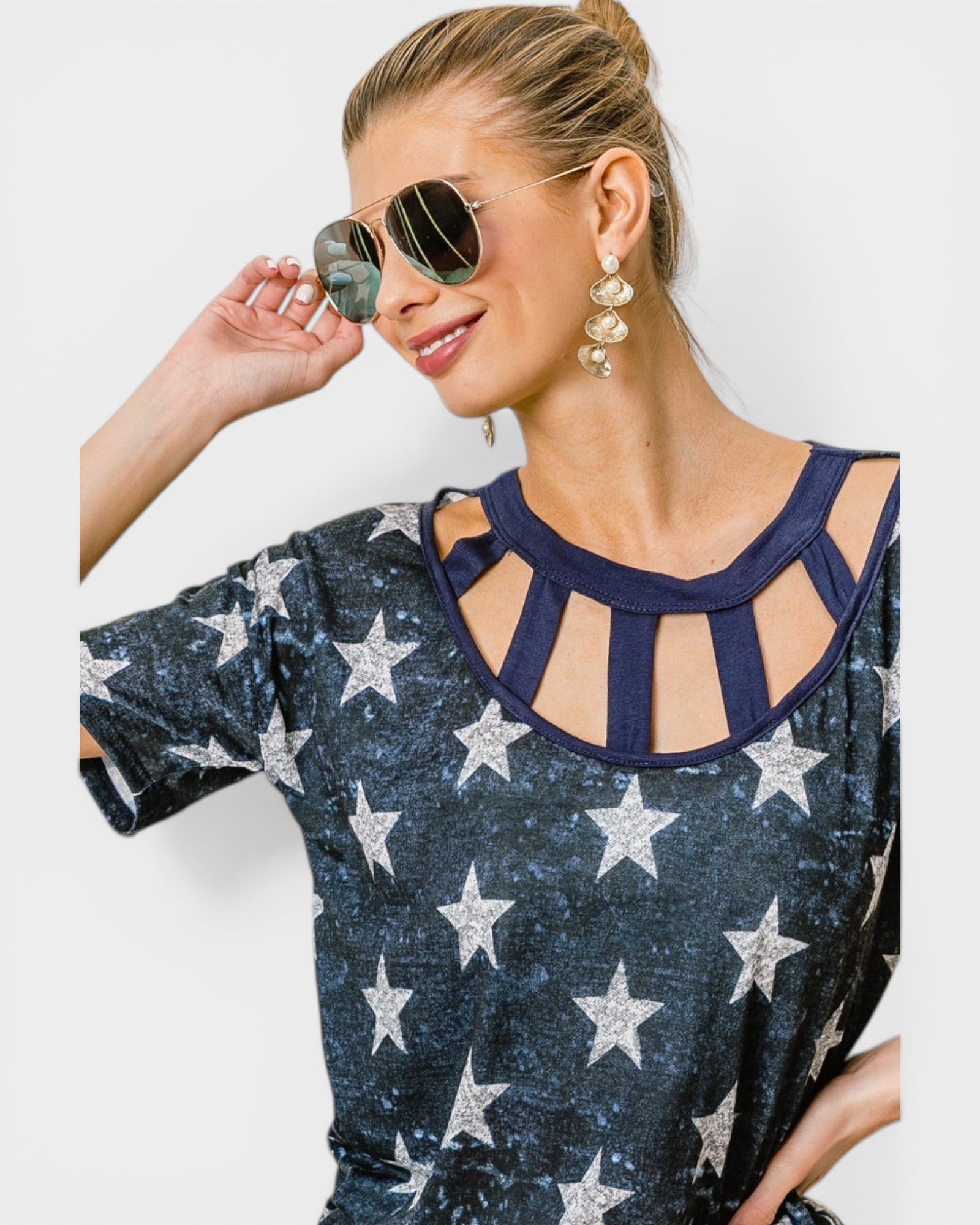 Woman wearing a navy blue top with star pattern and sunglasses on a white background