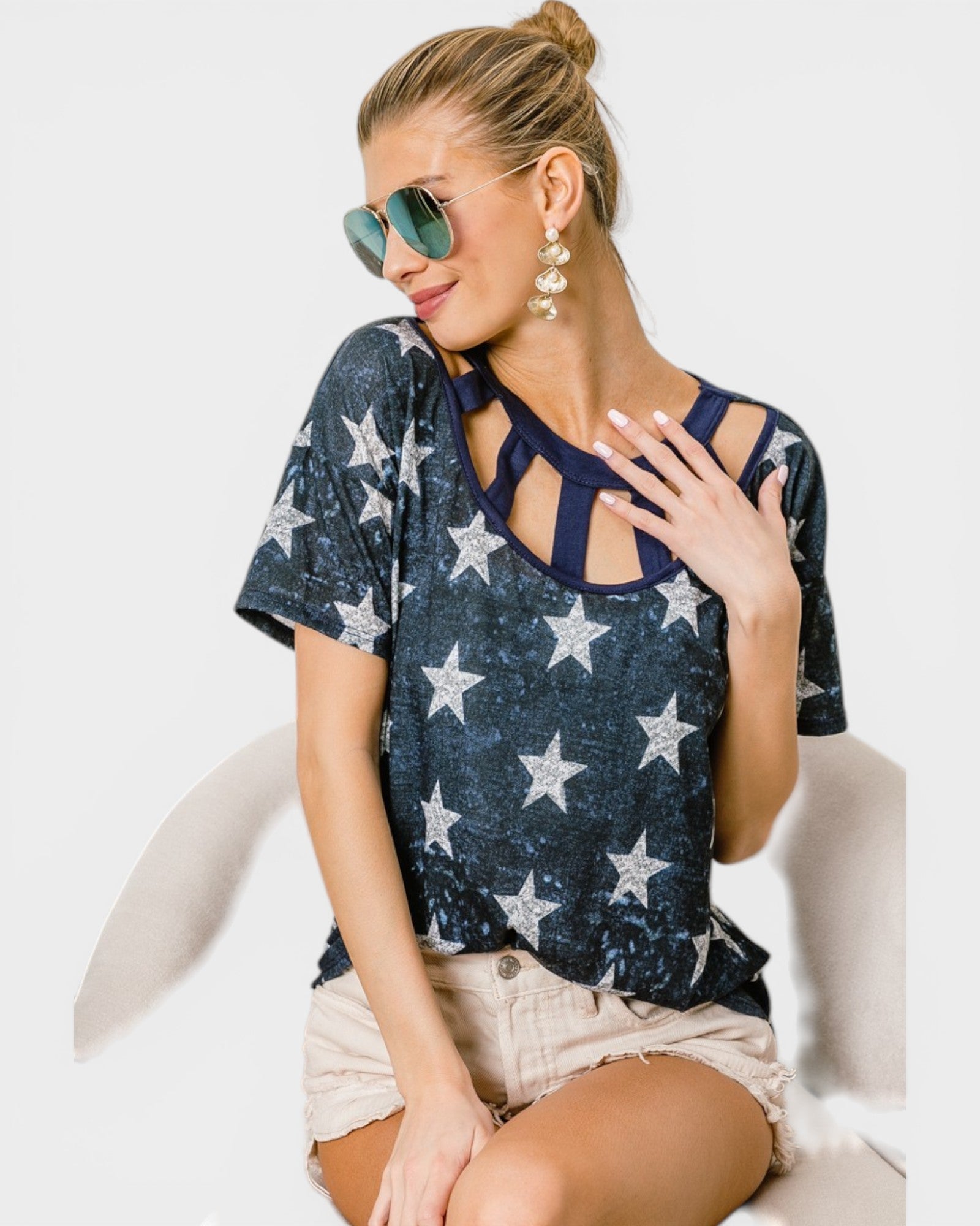 Woman wearing a navy blue top with star patterns and beige shorts on a white background