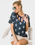 Woman wearing a navy blue top with star patterns and beige shorts on a white background