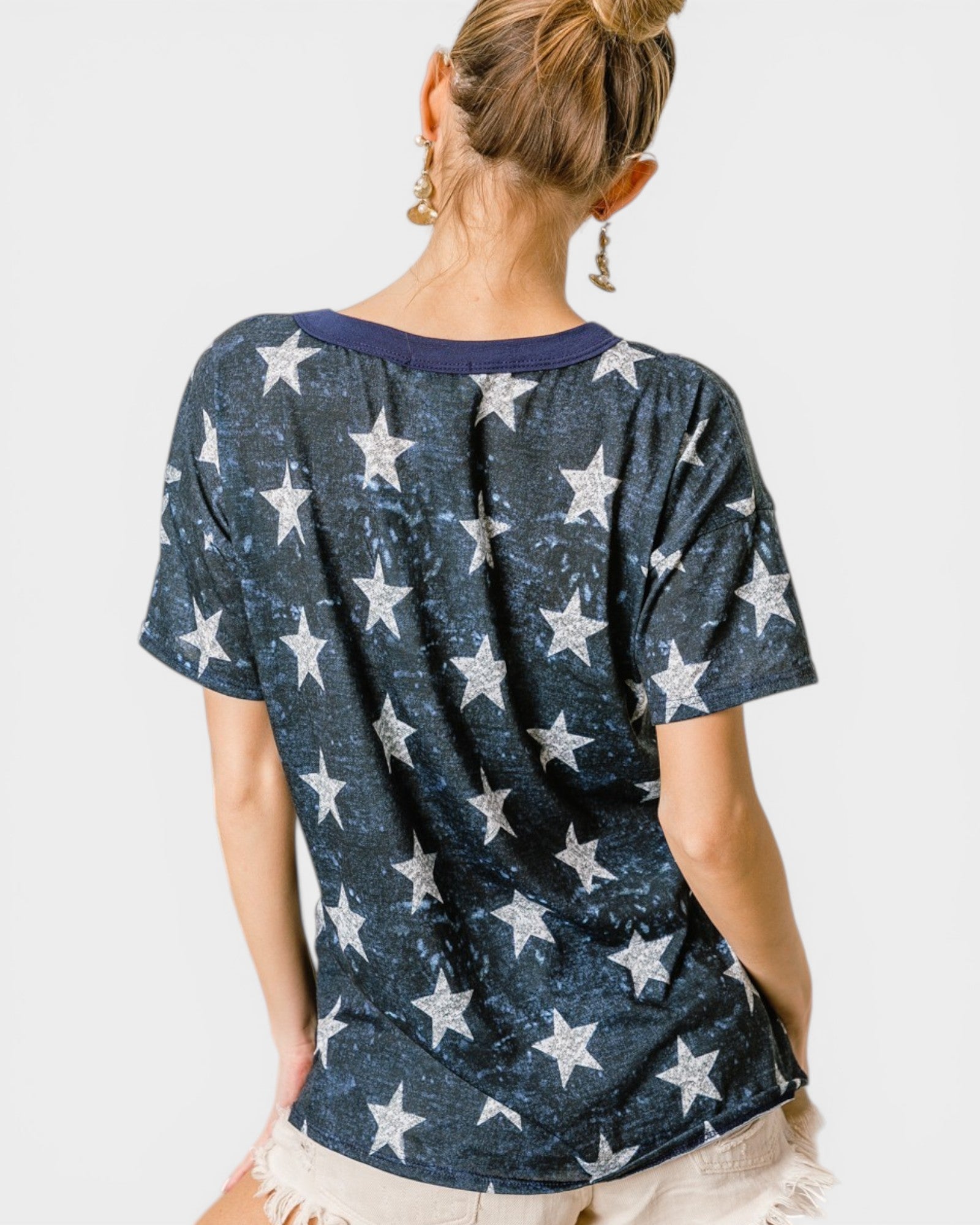 Woman wearing a navy blue t-shirt with white star pattern on a plain background