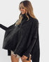 Woman wearing a dark gray poncho with fringe details on a white background