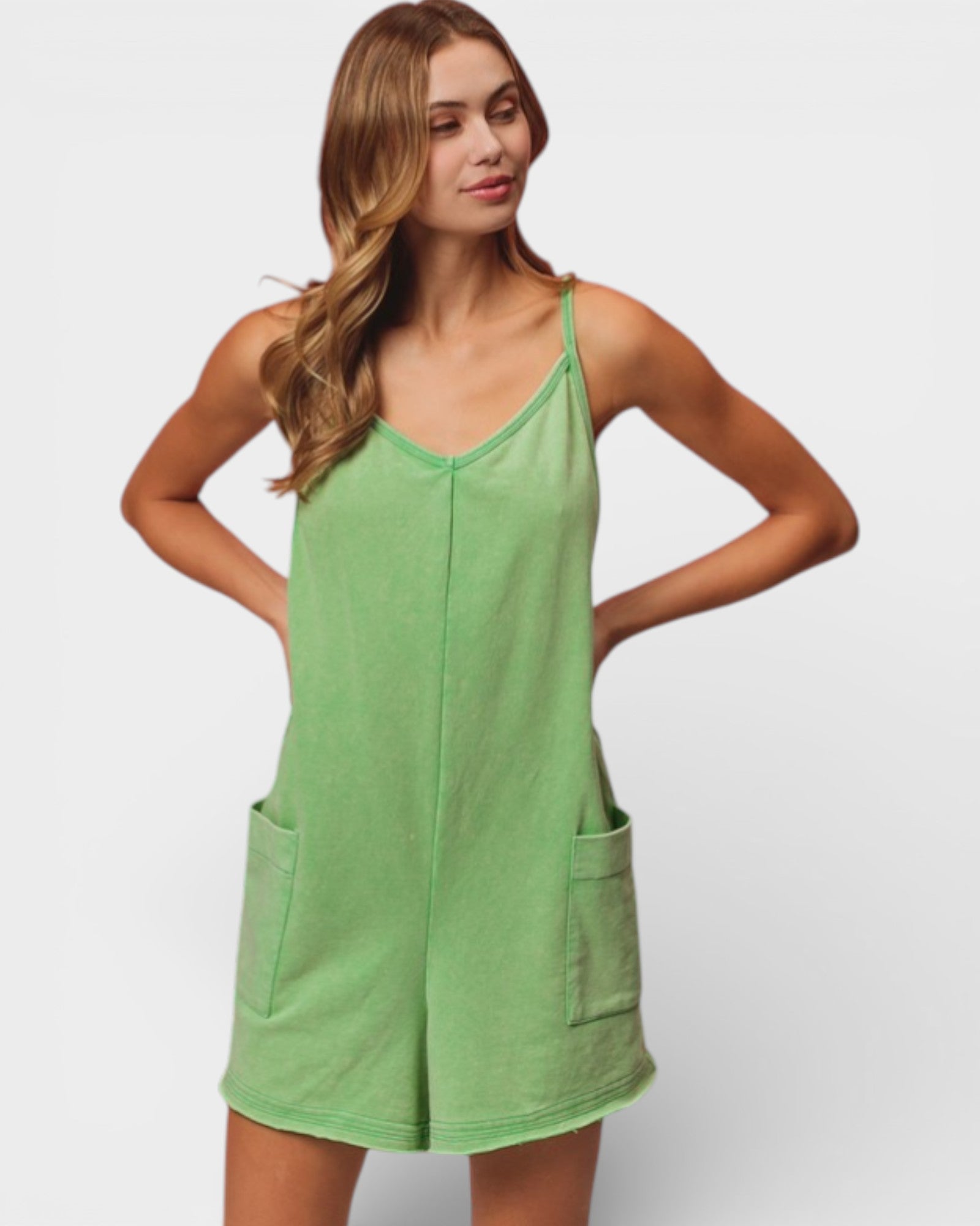 Woman wearing a green dress with pockets on a plain background
