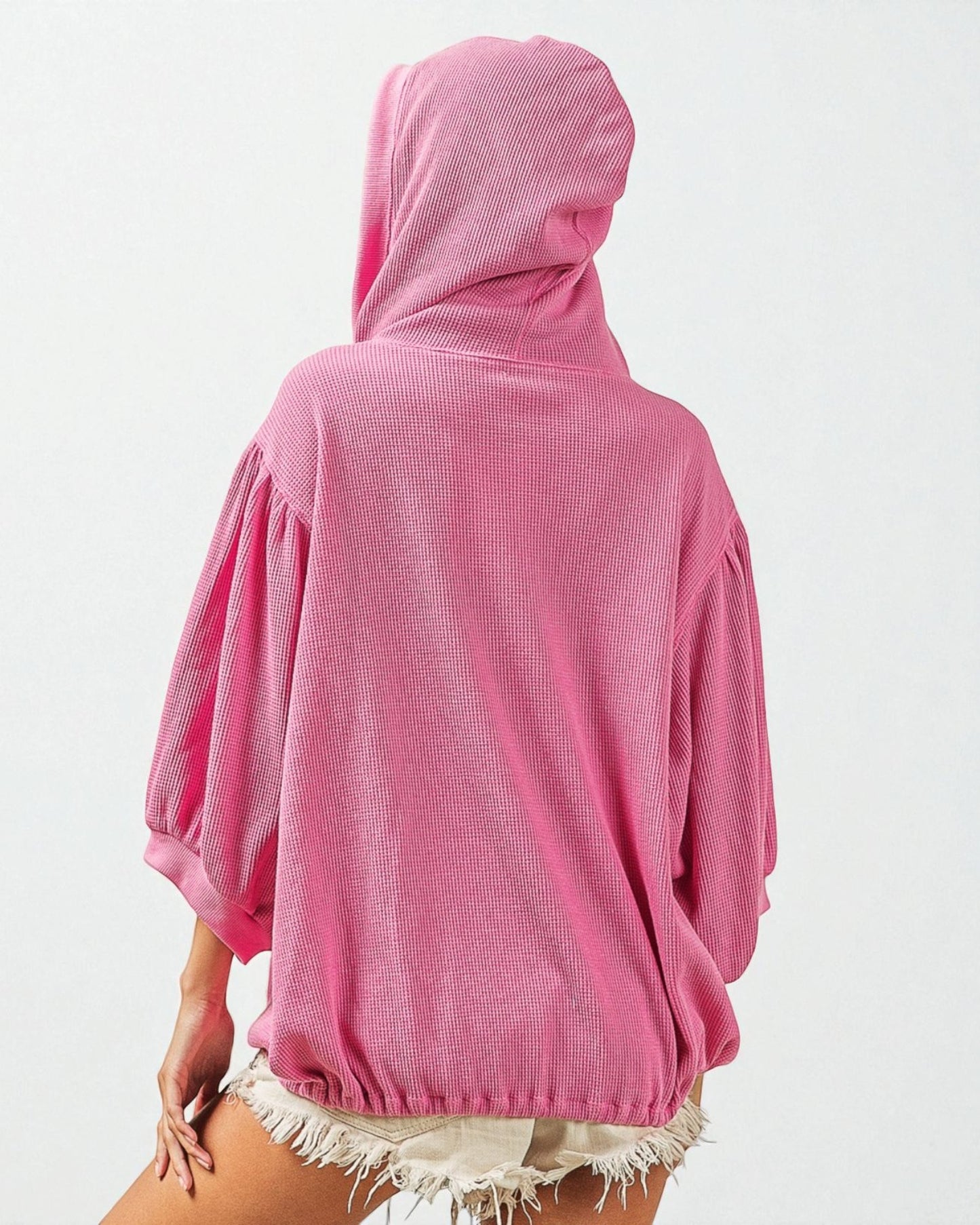 Person wearing a pink hooded garment on a white background