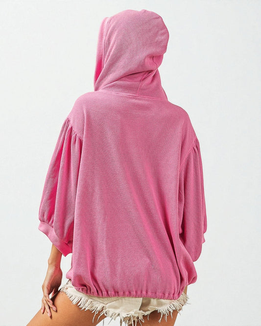 Person wearing a pink hooded garment on a white background