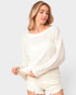 Woman wearing a white ribbed sweater and shorts on a light gray background