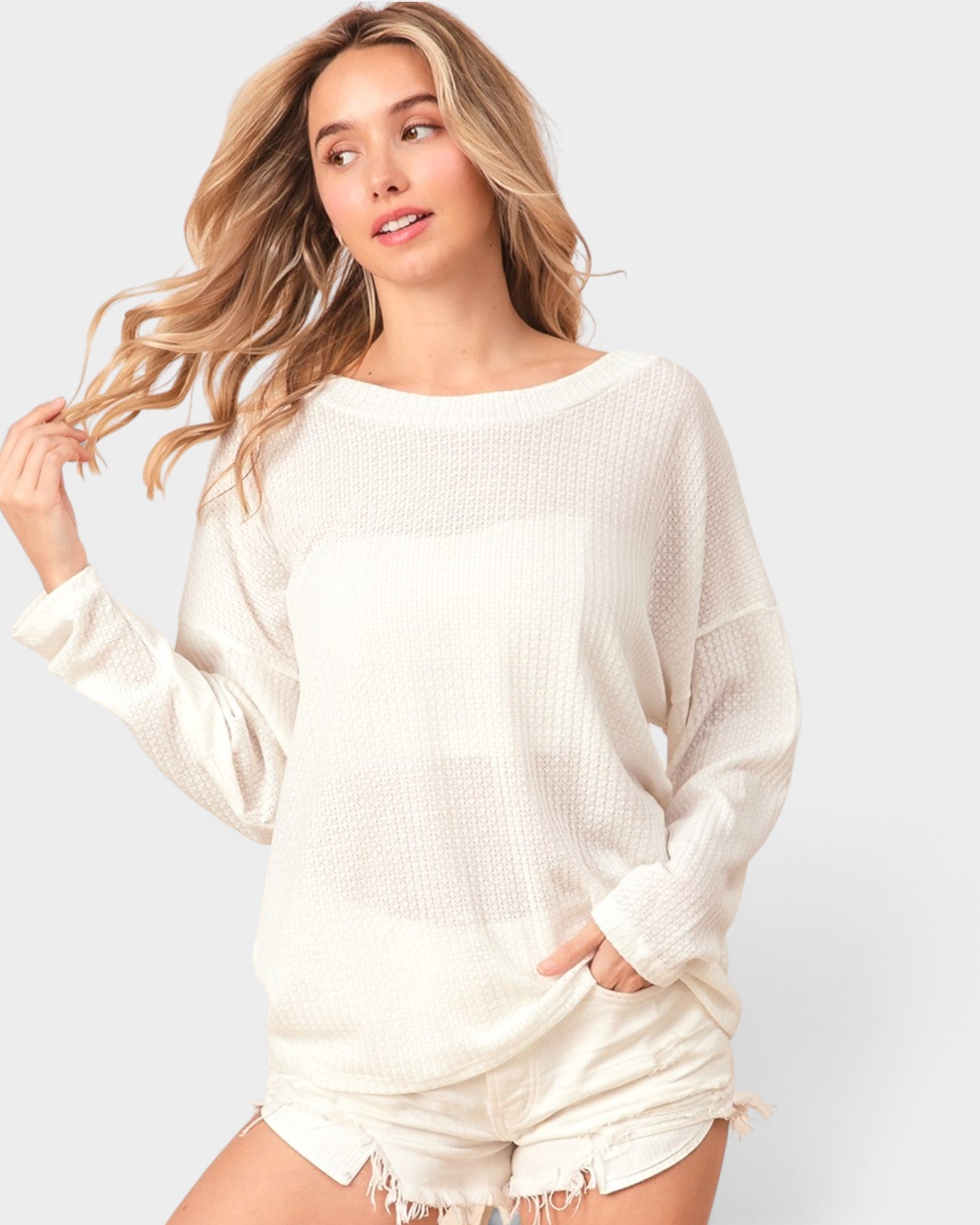 Woman wearing a white sweater and shorts on a light gray background