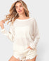 Woman wearing a white sweater and shorts on a light gray background