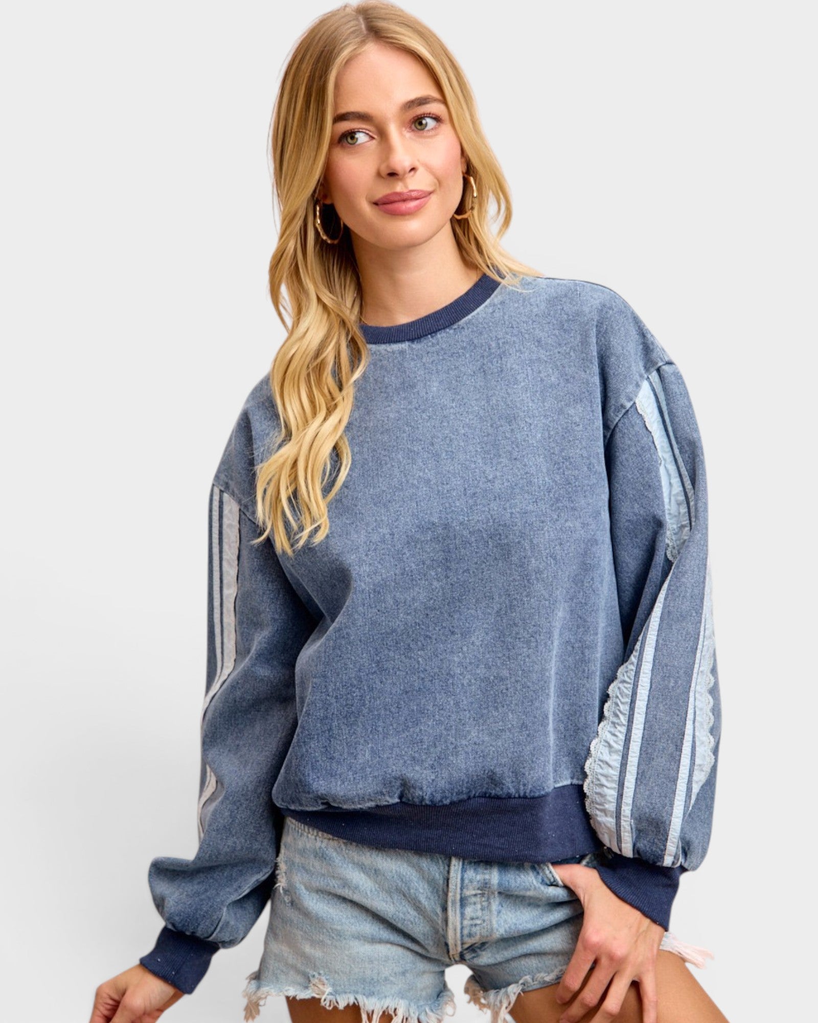 Woman wearing a blue distressed sweatshirt with white stripes on a white background