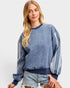 Woman wearing a blue distressed sweatshirt with white stripes on a white background