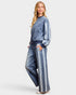 Woman wearing a blue denim outfit with white stripes on a light gray background