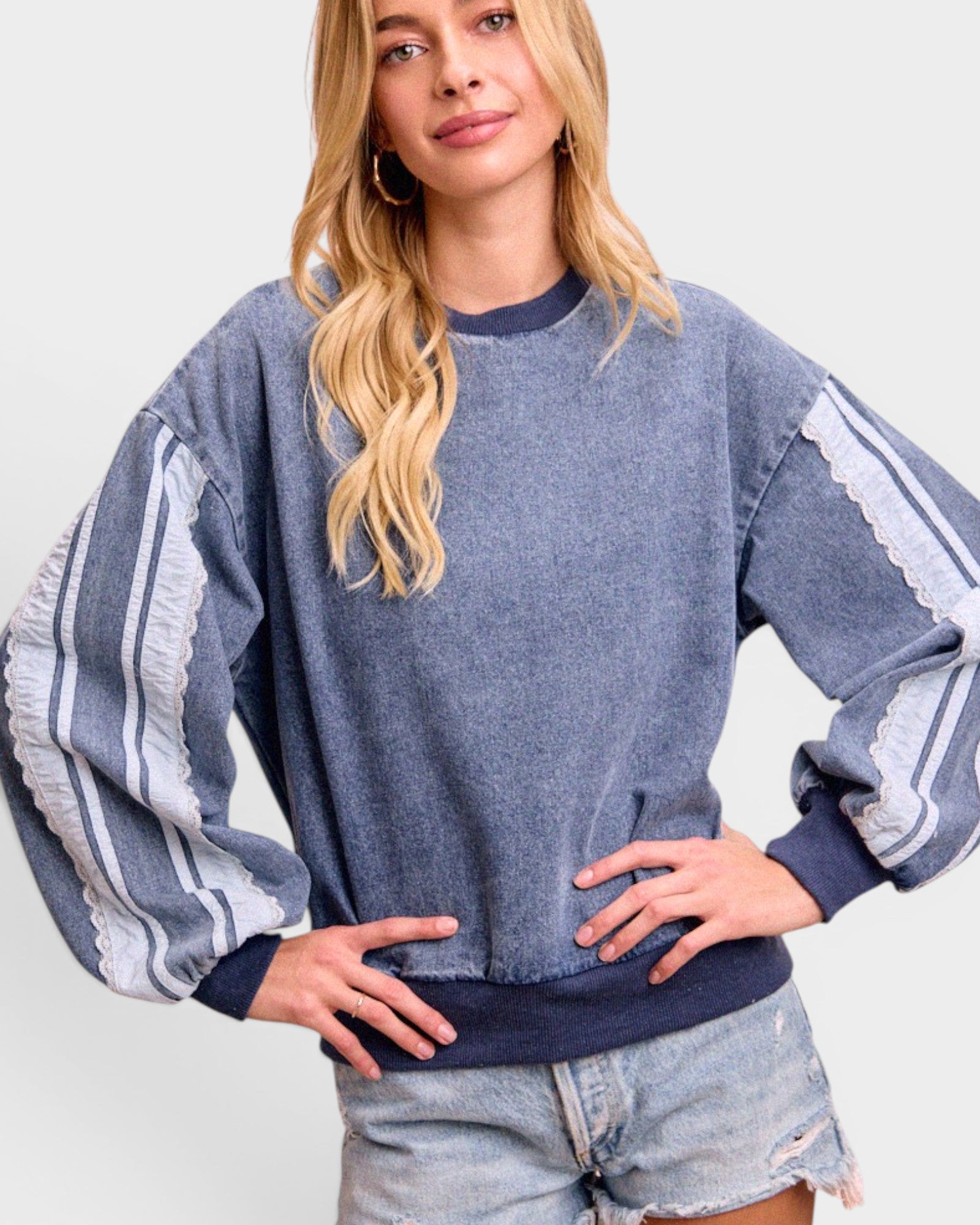Woman wearing a blue sweater with white stripes on a plain background