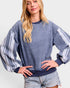 Woman wearing a blue sweater with white stripes on a plain background