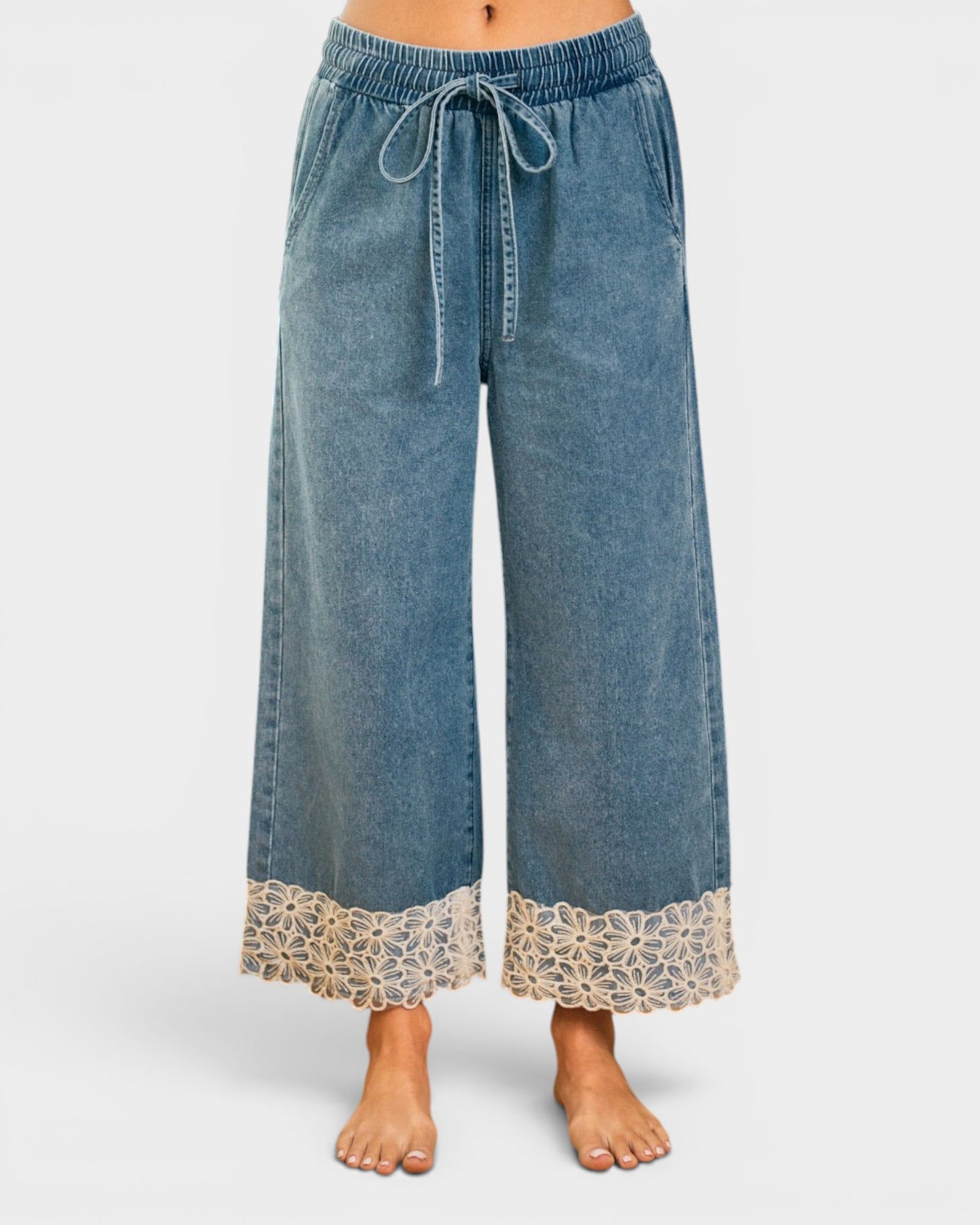 Blue denim pants with lace trim on a white background
