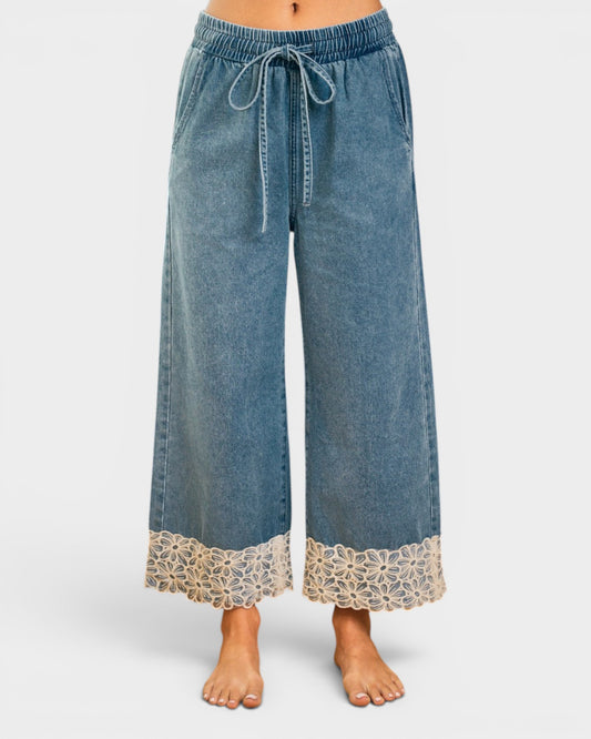 Blue denim pants with lace trim on a white background