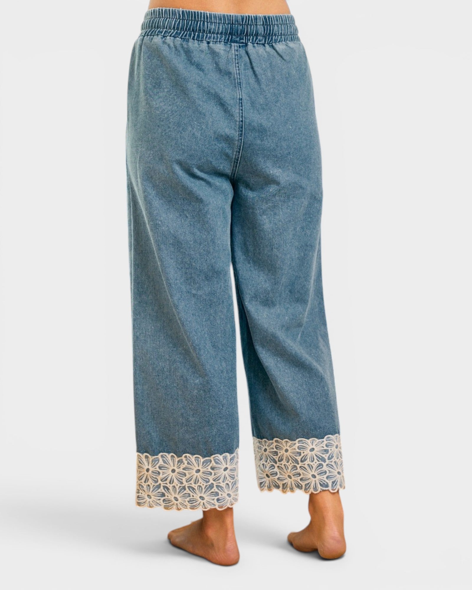 Blue denim pants with lace trim on a white background