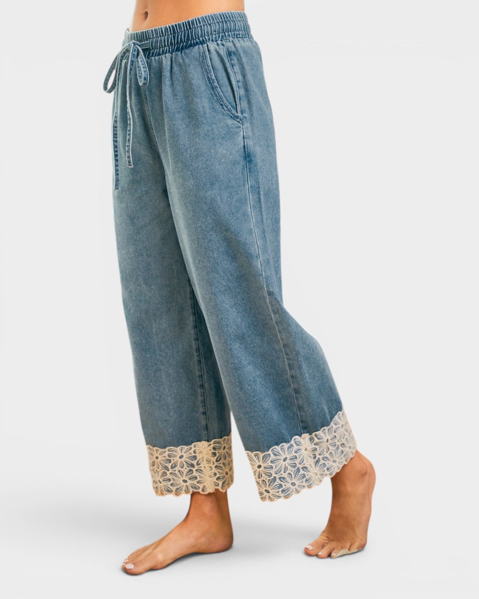 Blue denim pants with lace cuffs on a white background