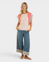 Woman wearing a pink top with floral sleeves and blue jeans on a white background