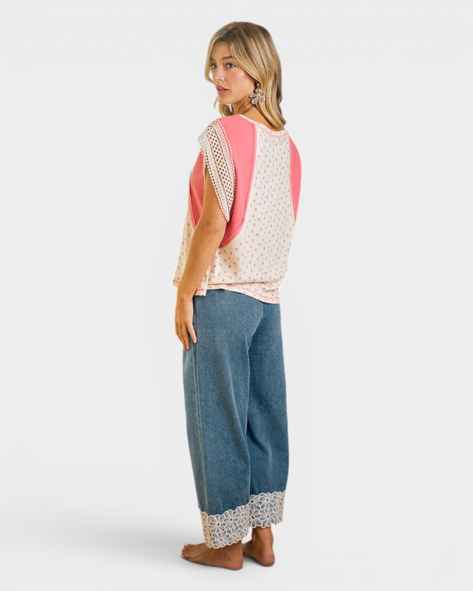 Woman wearing a sleeveless top with lace details and wide-leg jeans on a white background