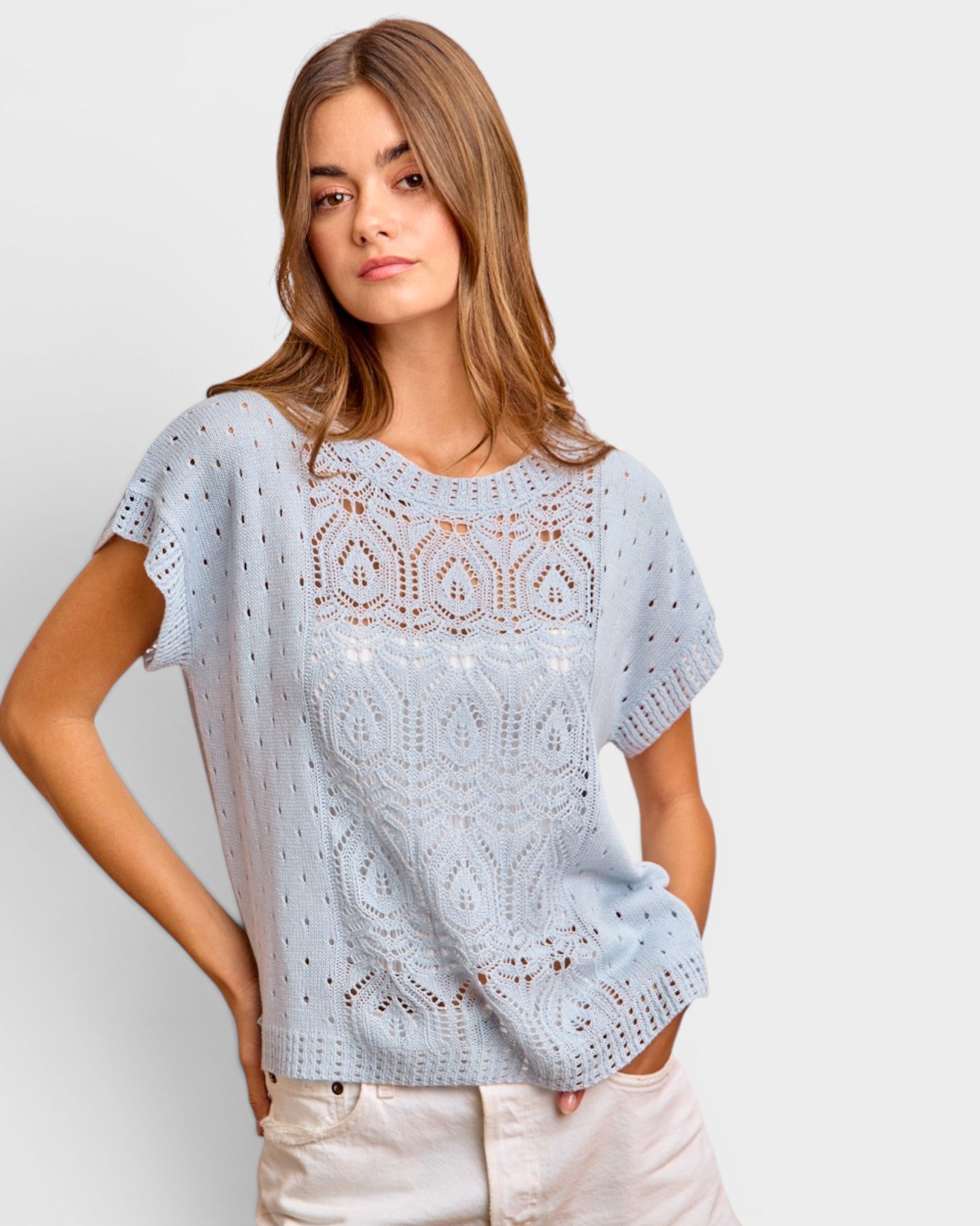 Woman wearing a light blue lace top against a plain background