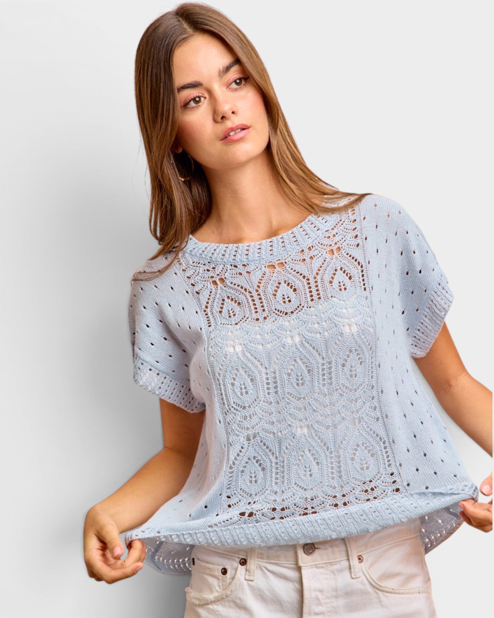 Woman wearing a light blue crochet top against a plain background