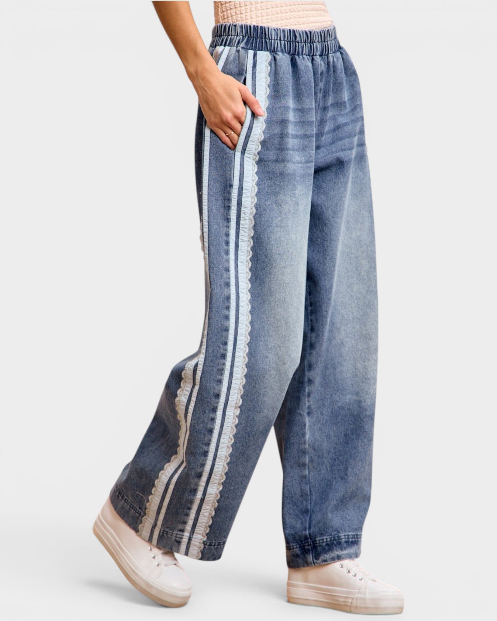 Blue denim pants with white lace trim on a light gray background