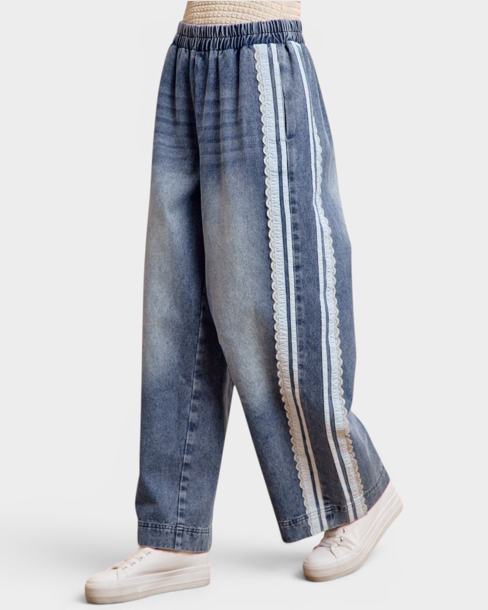 Blue denim pants with white stripes worn by a person on a light gray background