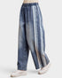 Blue denim pants with white stripes worn by a person on a light gray background