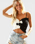 Woman wearing a black and white crop top with denim shorts on a light gray background