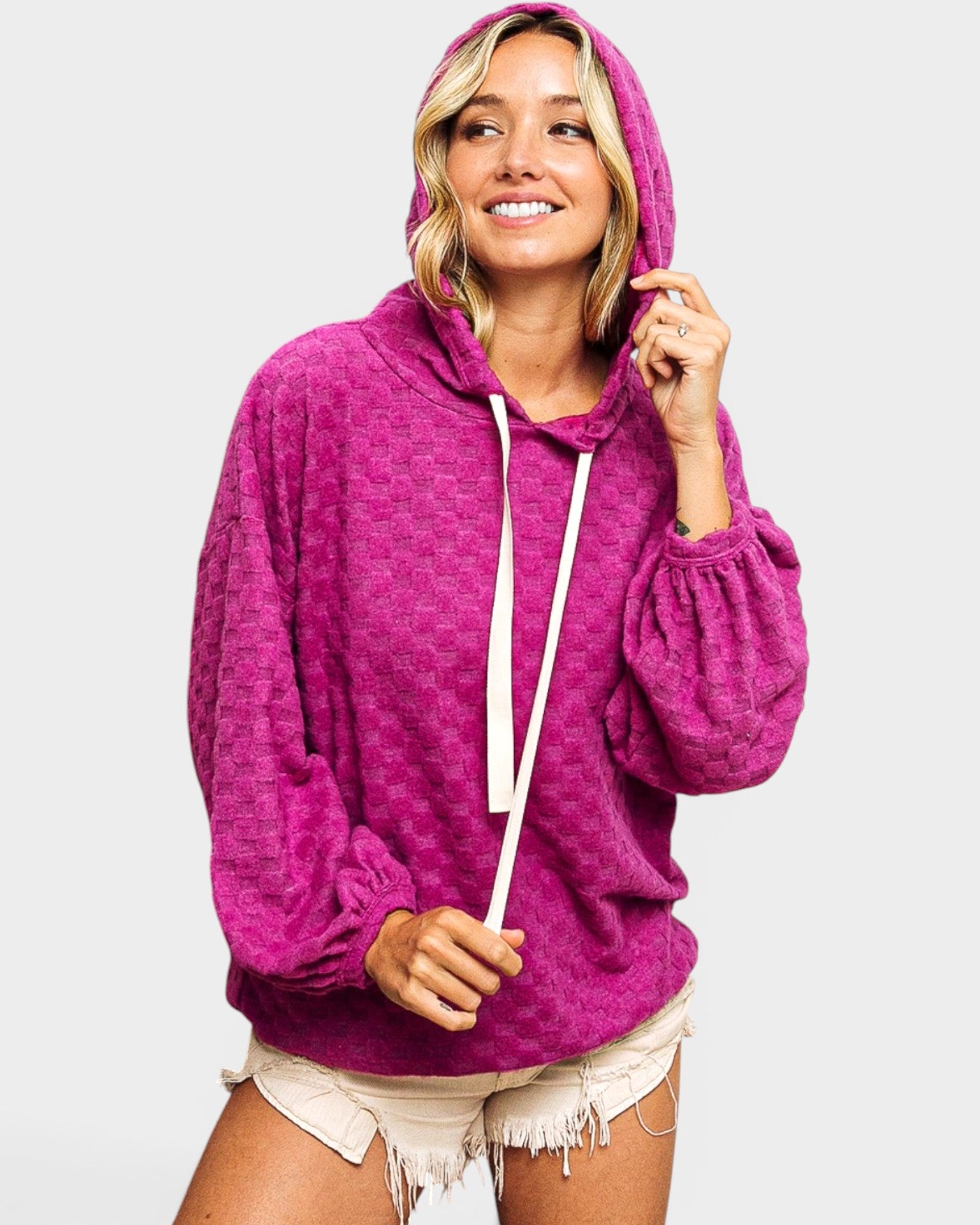 Woman wearing a pink hoodie on a plain background