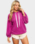 Woman wearing a pink hoodie and white shorts on a light purple background