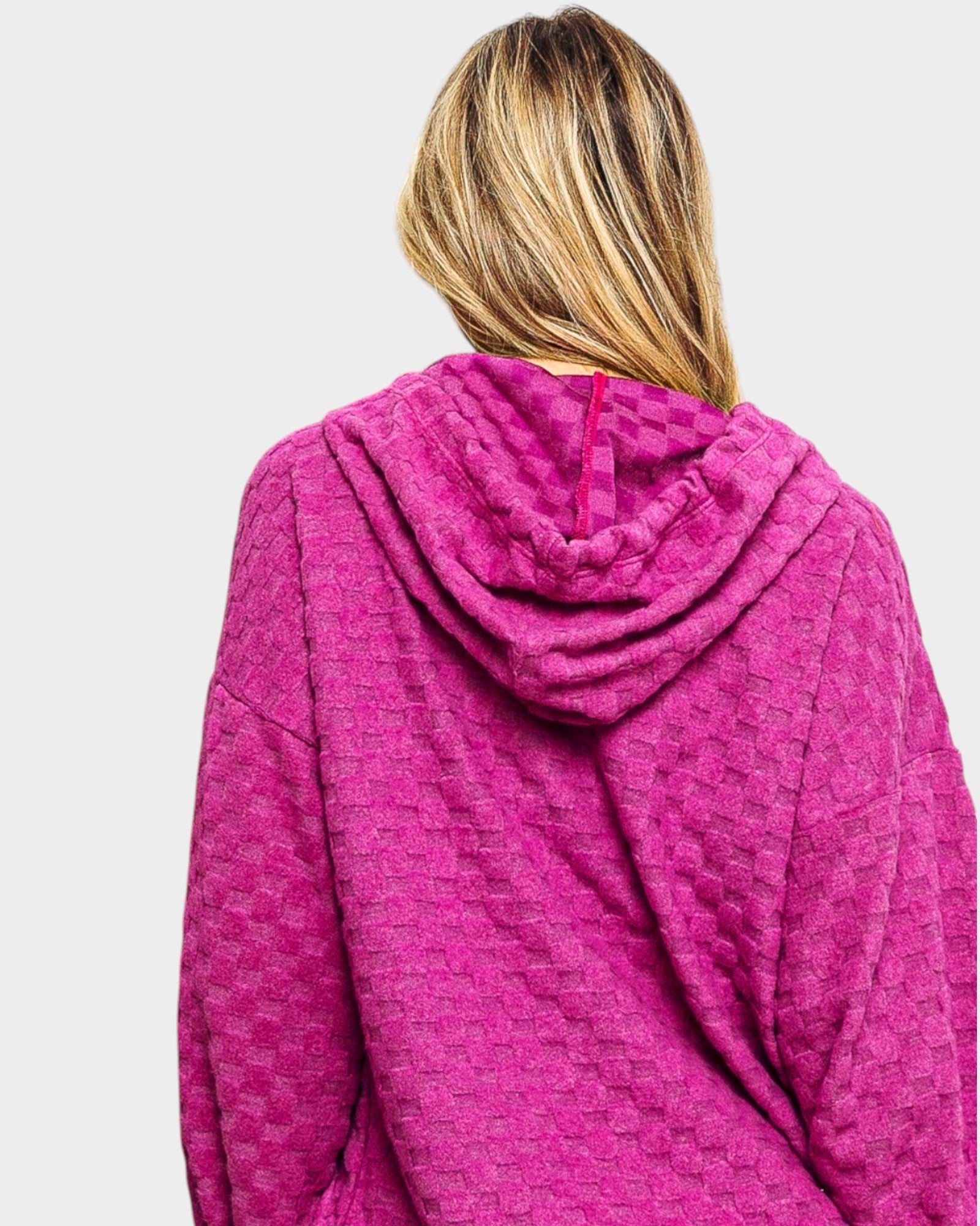 Person wearing a pink textured hoodie on a light gray background