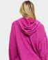 Person wearing a pink textured hoodie on a light gray background