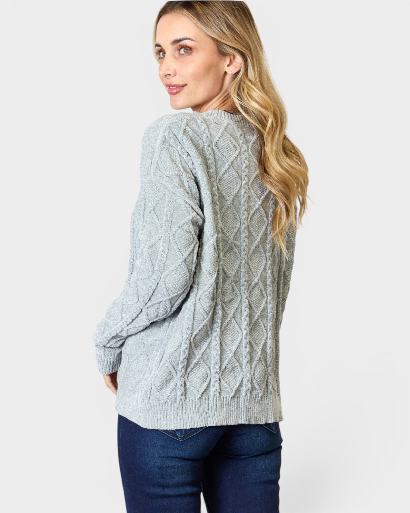 Woman wearing a gray cable knit sweater on a white background
