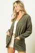 Woman wearing a green cardigan over a white top on a plain background