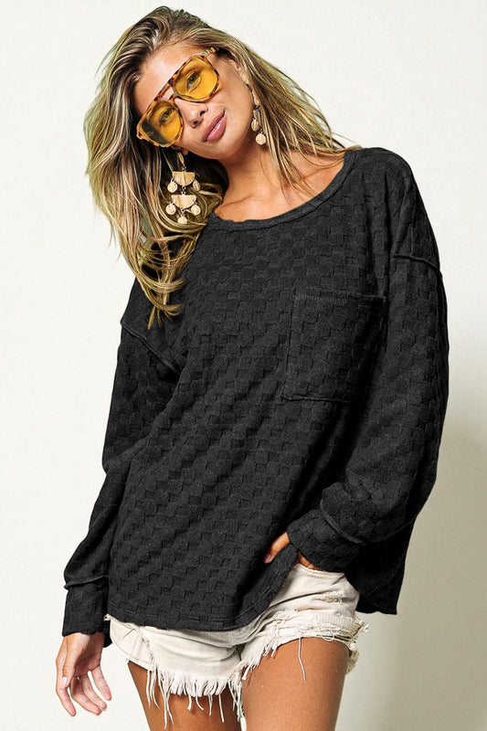 Woman wearing a black oversized sweater and white shorts with yellow sunglasses on a plain background