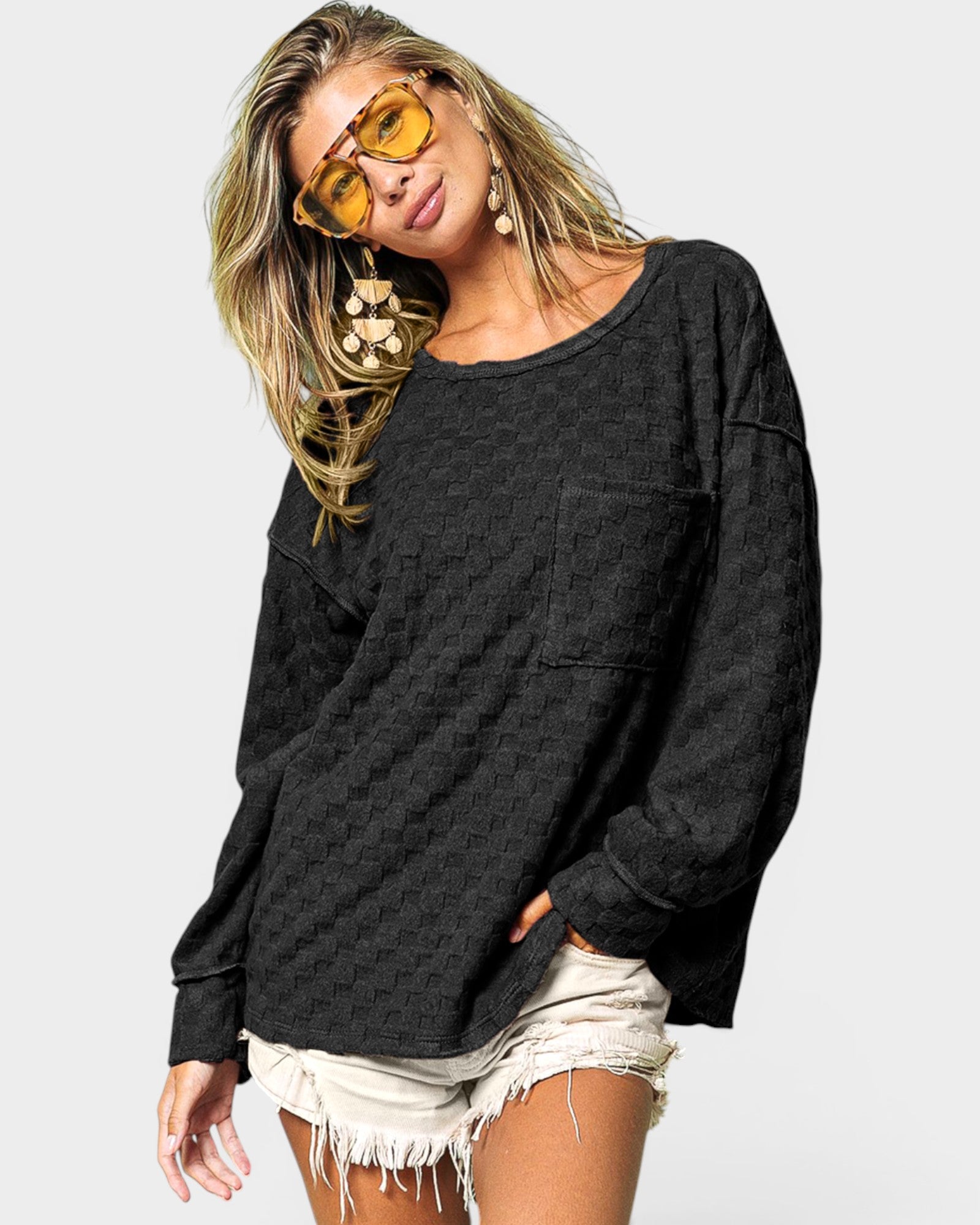Woman wearing a dark gray oversized sweatshirt and white shorts with yellow sunglasses on a light gray background