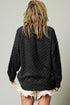 Person wearing a black quilted jacket with a plain background