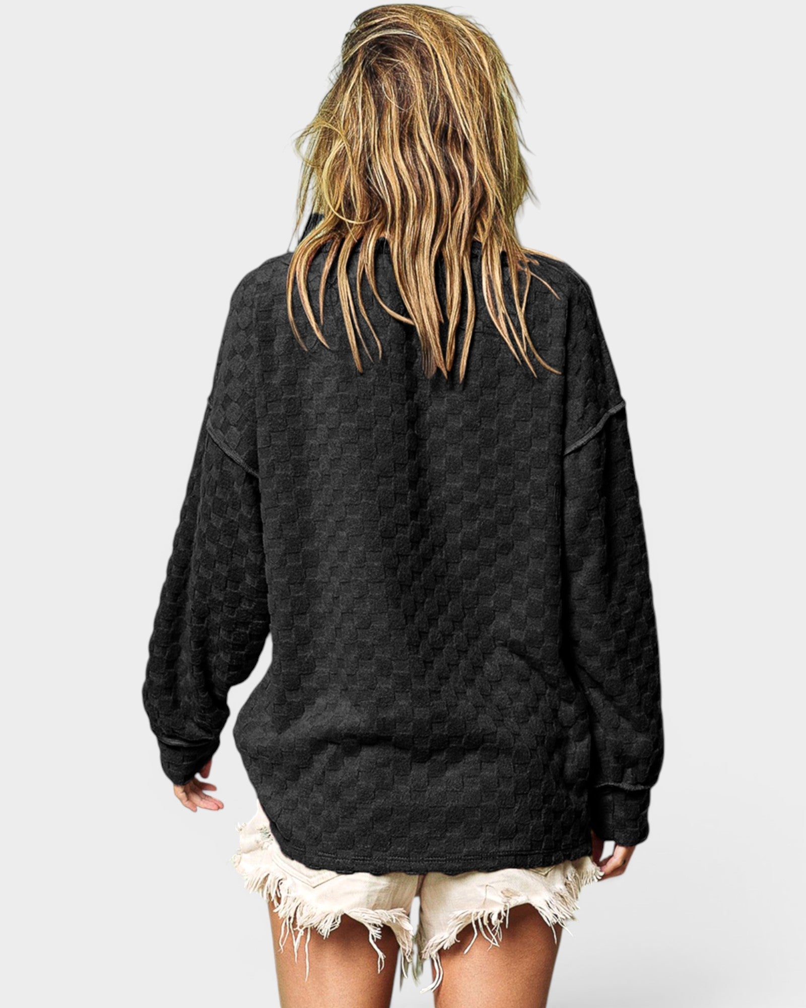 Person wearing a black oversized sweatshirt with a plain background