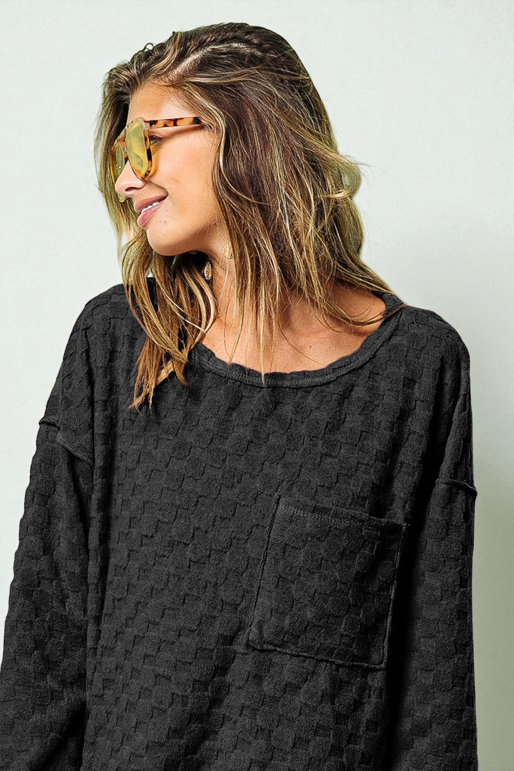 Woman wearing a dark gray textured shirt against a plain background