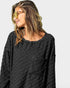 Woman wearing a dark gray textured shirt against a plain background