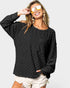 Woman wearing a black long-sleeve top and white shorts with sunglasses on a plain background