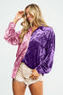 Woman wearing a two-tone pink and purple velvet shirt with white shorts on a light gray background