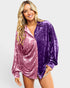 Woman wearing a two-tone purple velvet shirt on a plain background