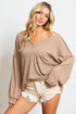 Woman wearing a beige sweater and white shorts on a plain background
